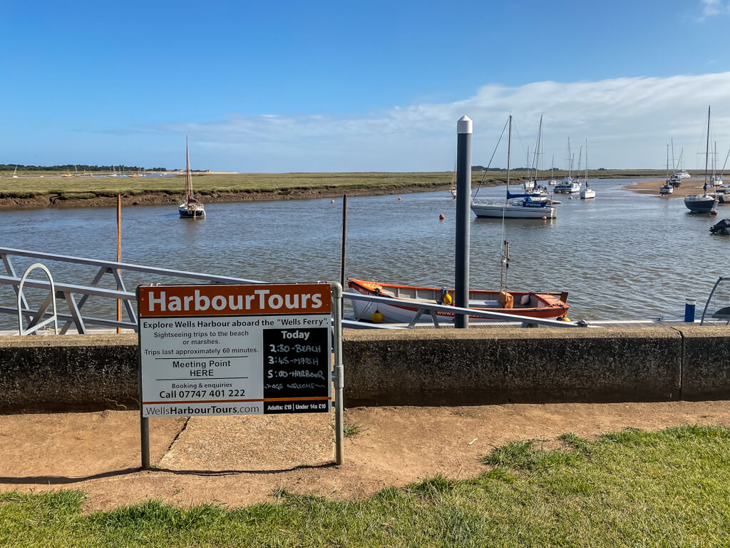 sign about wells harbour tours with boat in the background in the harbour