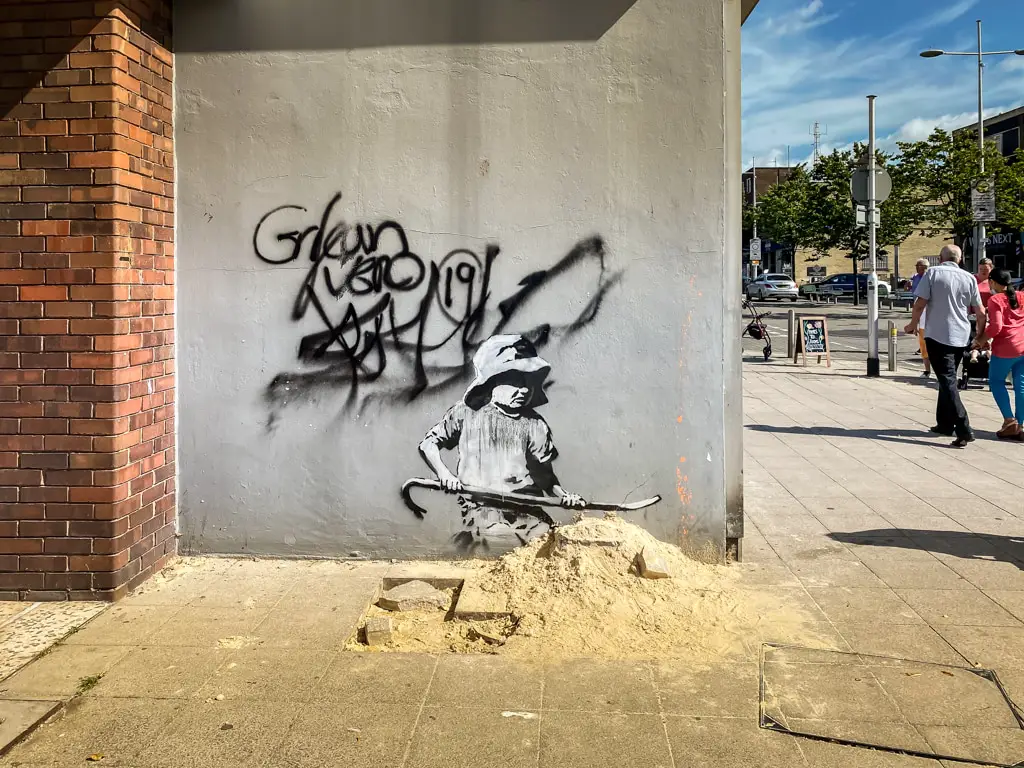 girl with sand on london road in lowestoft by banksy