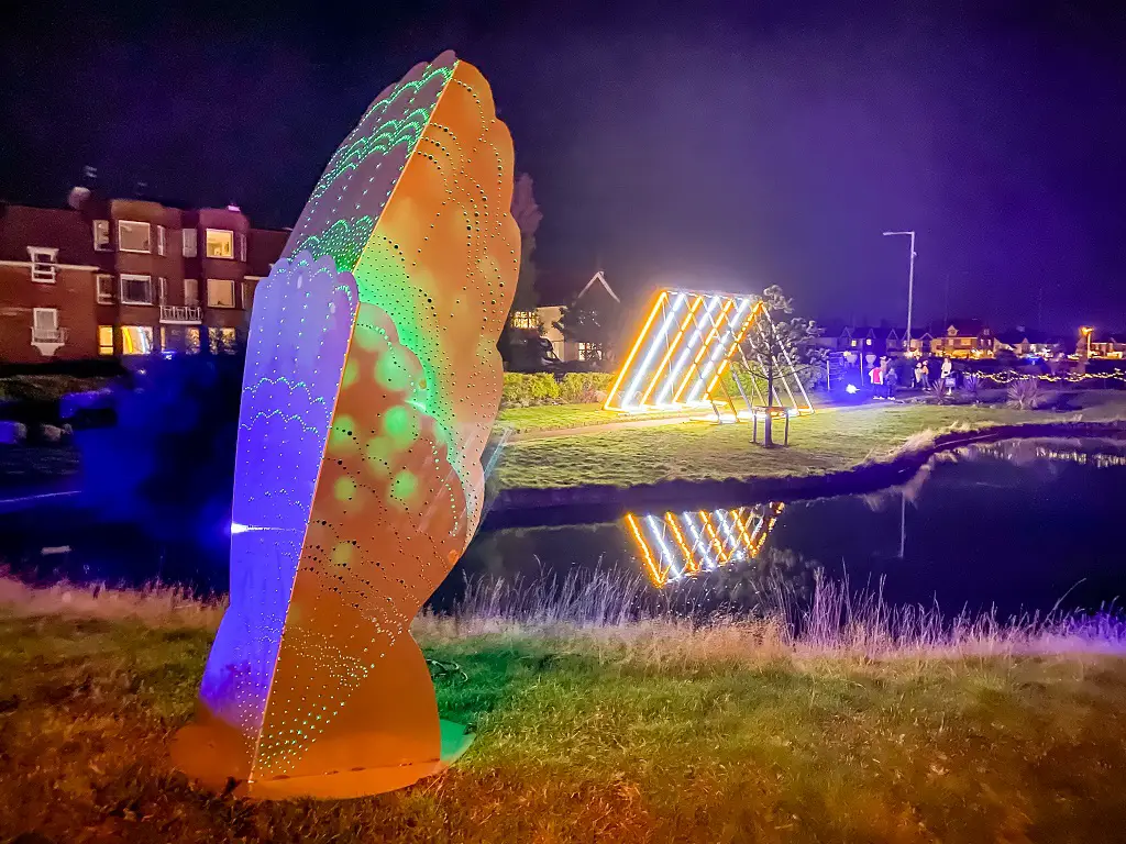 shell shaped sculpture with a light sculpture triangle in the background at fire on the water