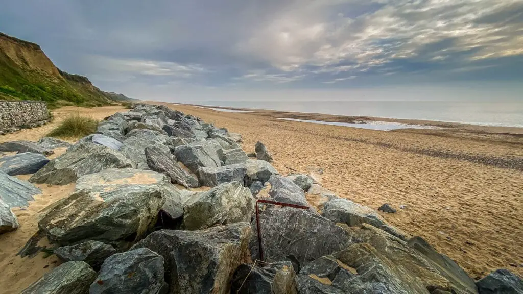 view looking up California beach with large rocks sand and cliffs