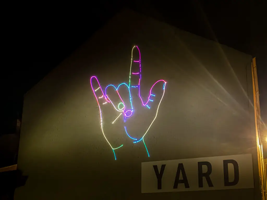 a neon hand doing a sign language love sign