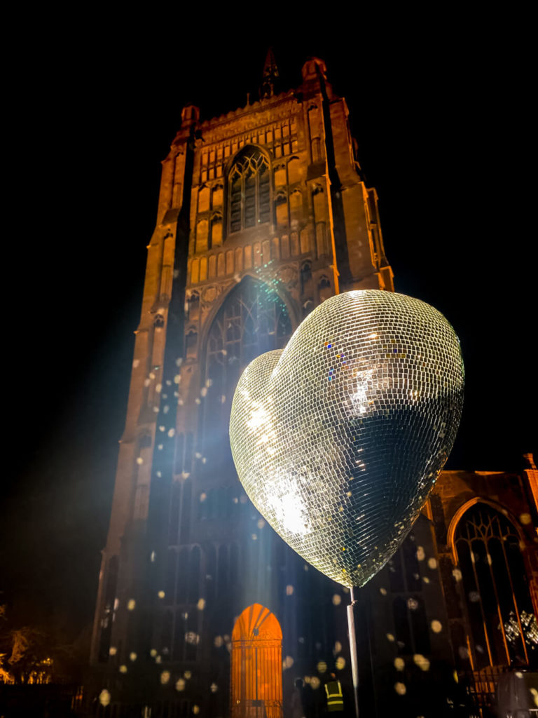 heart shaped disco ball with the tower of St. Peter Mancroft church in the background