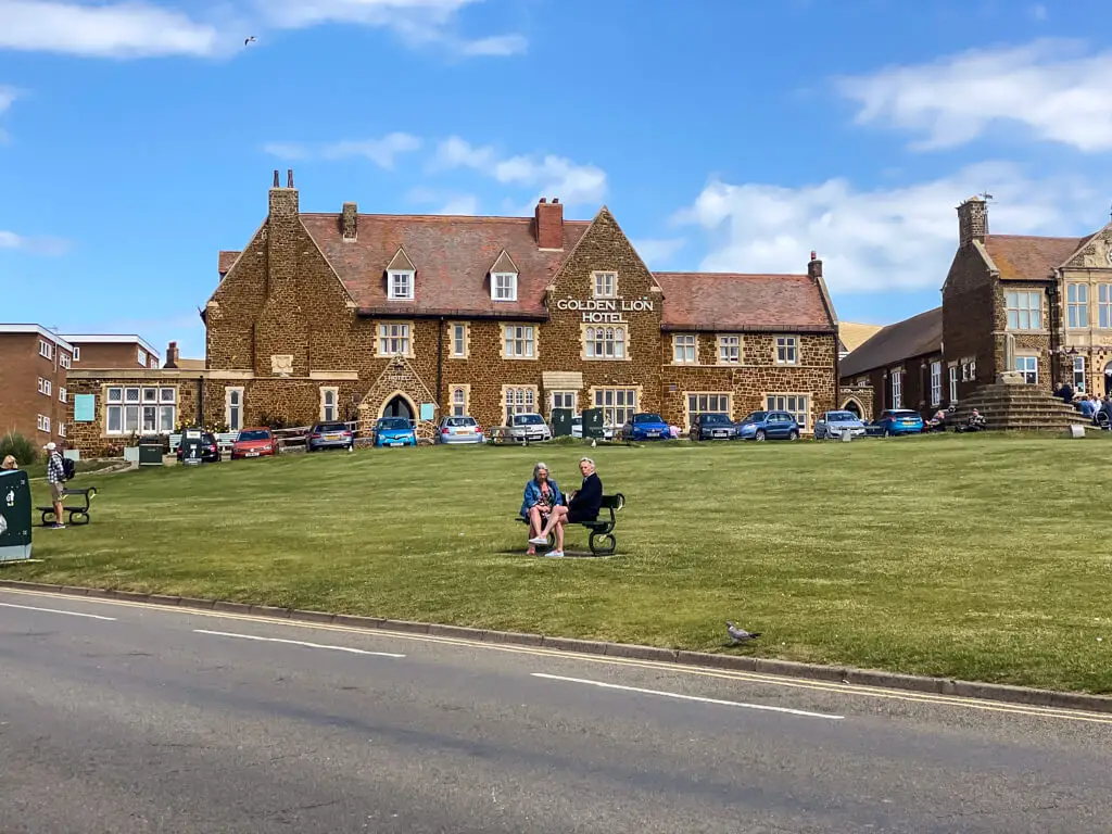 golden lion hotel with two people sitting on a bench in front of it