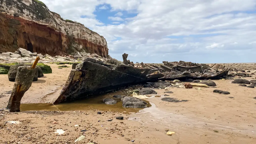 ruins of a shipwreck on hunstanton beach with cliffs in the background