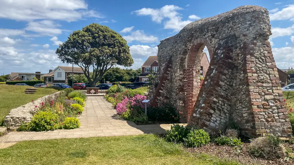 the ruins consist of a stone wall with an arch surrounded by flowers