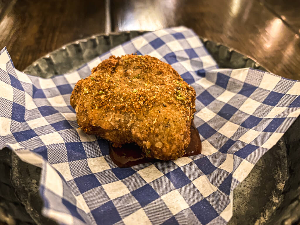 small piece of fried rabbit with brown sauce on blue and white napkin