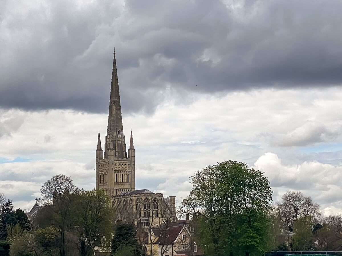 norwich cathedral with dark rain clouds above it