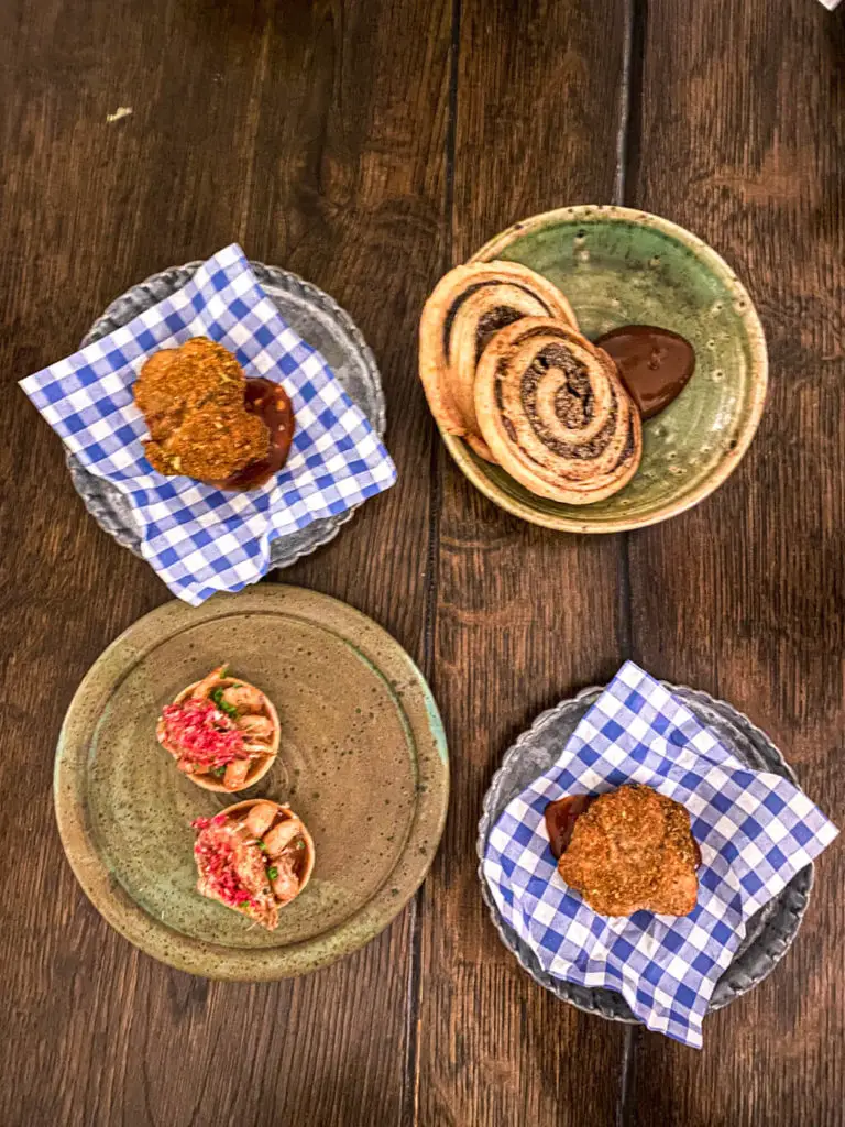 overhead shot of 4 with starters - fried rabbit (presented on two plates with blue and white napkin), mushroom twizzler, and brown shrimp tartlet