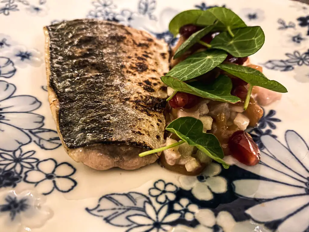 piece of mackerel with small salad on blue and white plate
