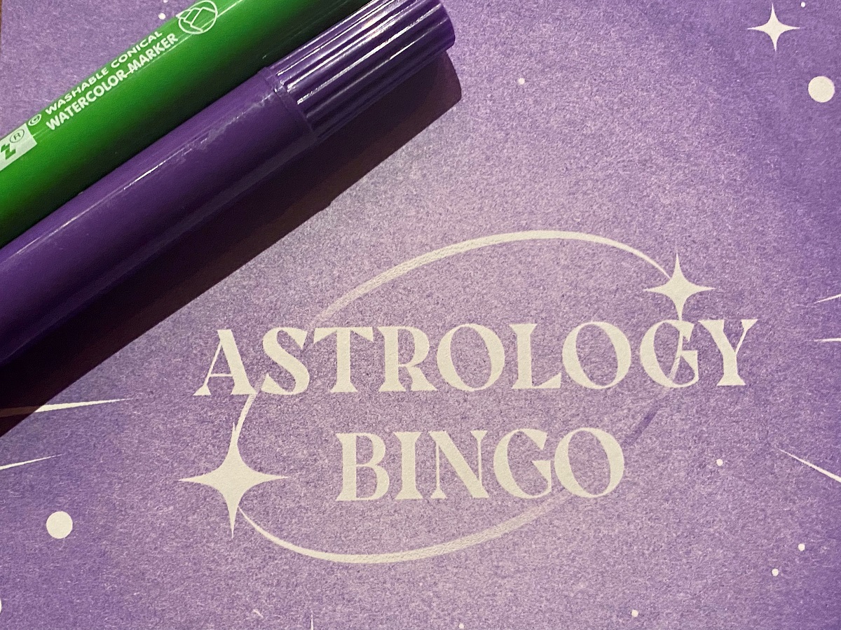 paper where astrology bingo is written with two bingo markers