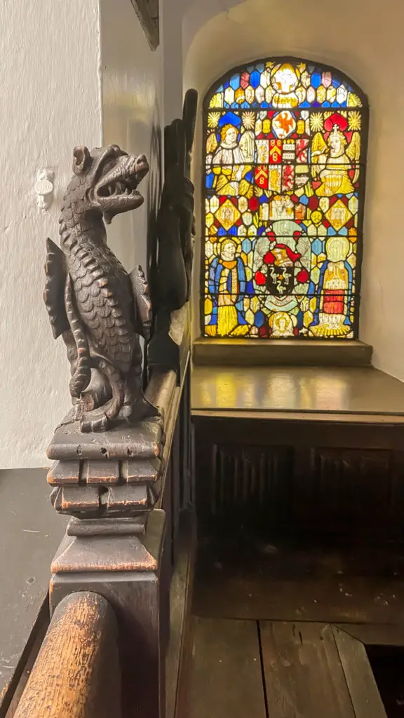 view of wooden dragon carving and one of the stained glass windows