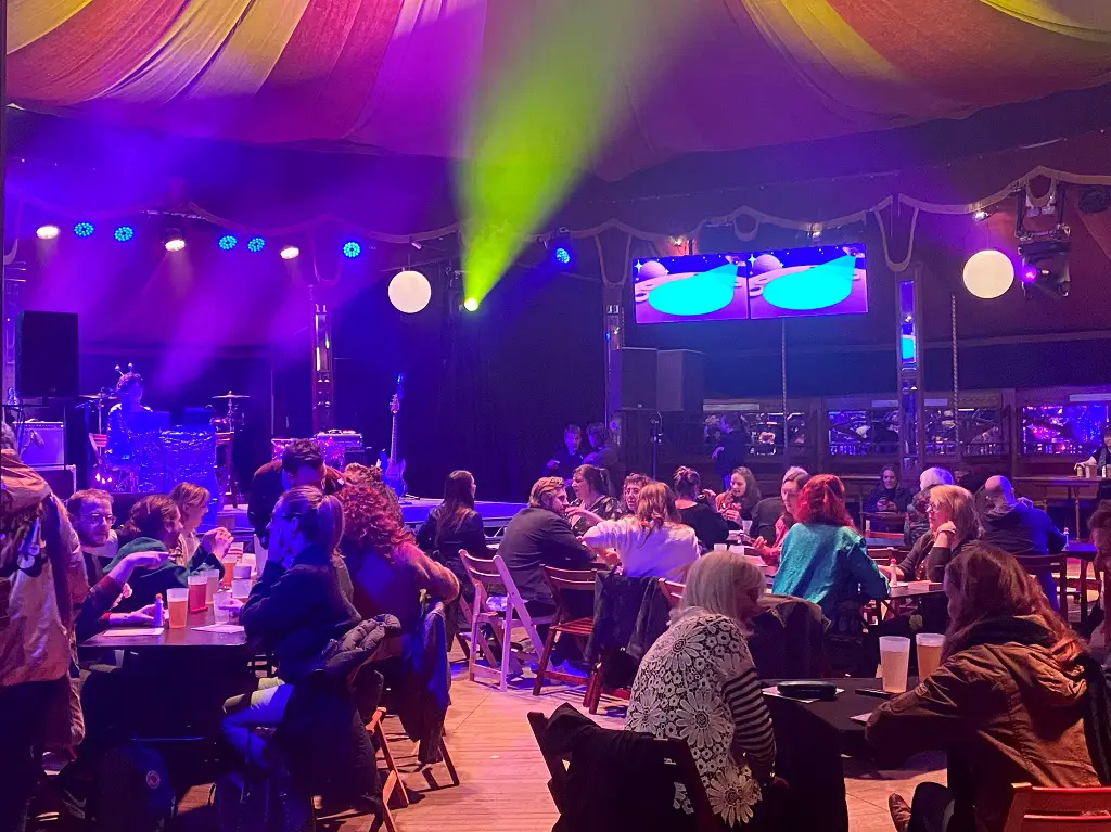 people sitting at tables inside the Adnams Spiegeltent ready for astrology bingo
