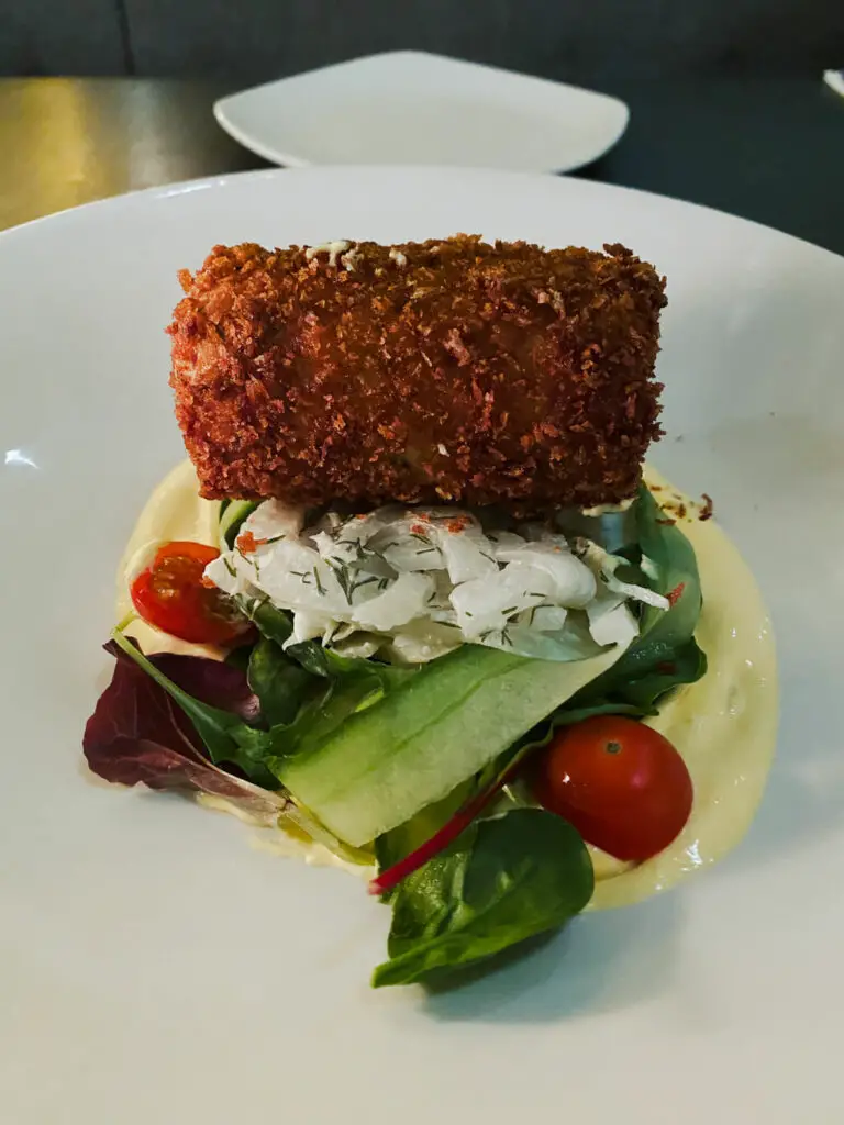 crab fritter on top of some vegetables and a creme sauce