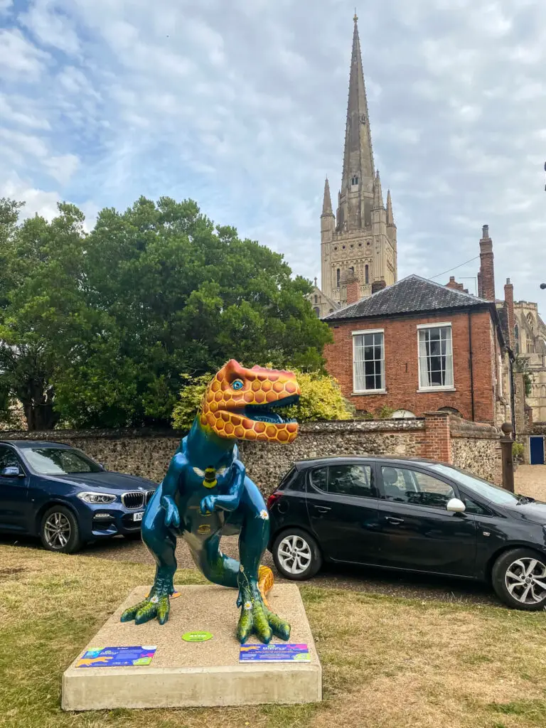 t-rex sculpture with car and norwich cathedral in the background
