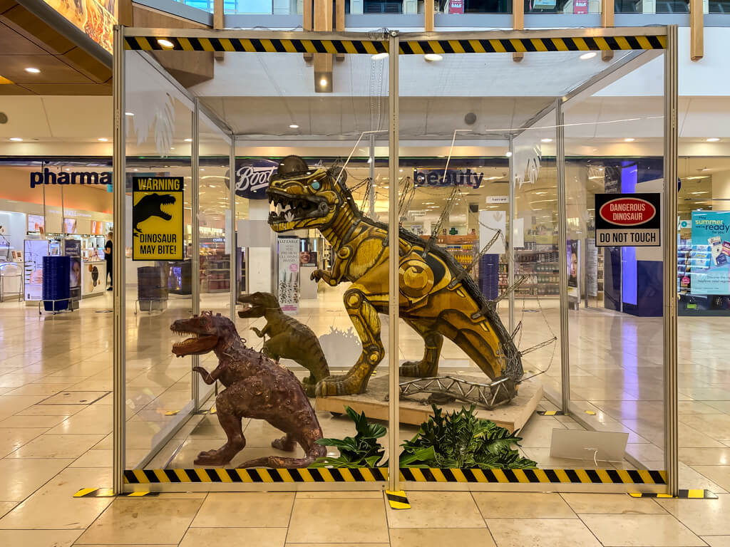 t-rex with two smaller trexes inside clear cage