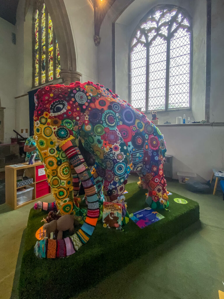 mammoth covered in knitted flowers inside a church