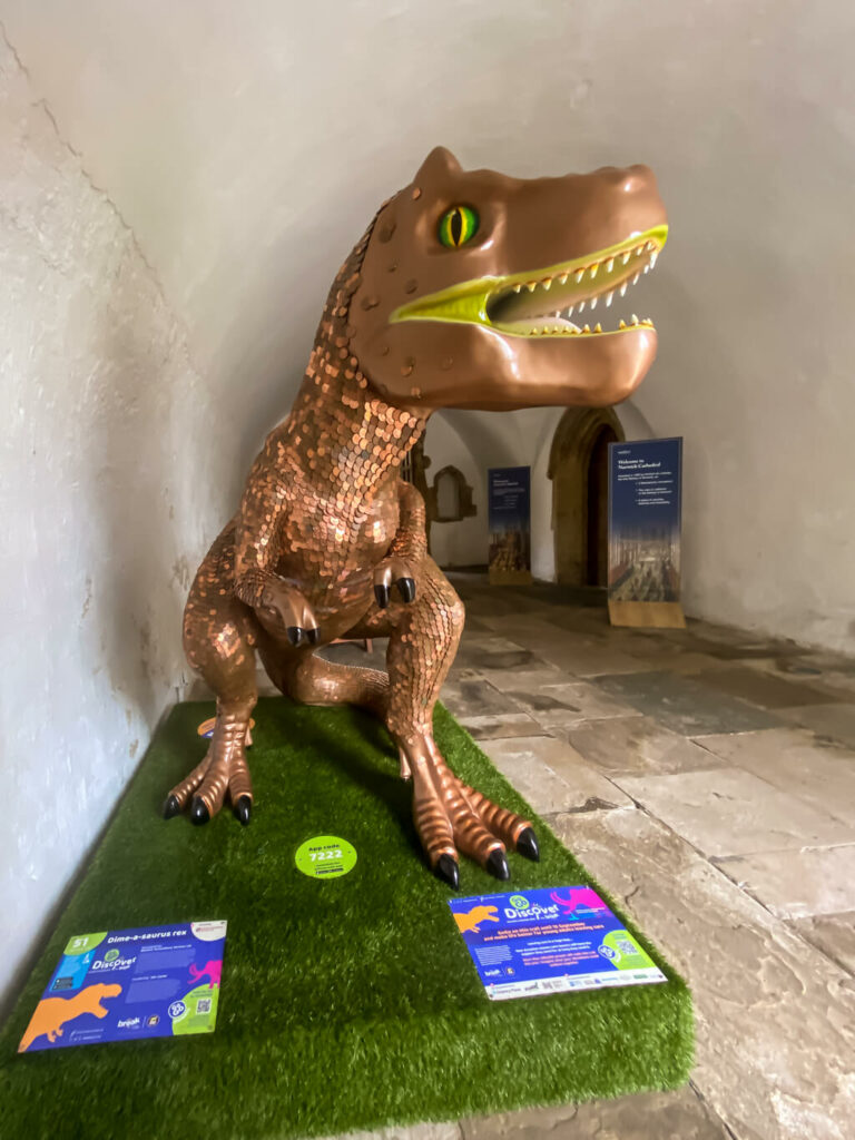 t-rex sculpture covered in coins in what looks like a tunnel