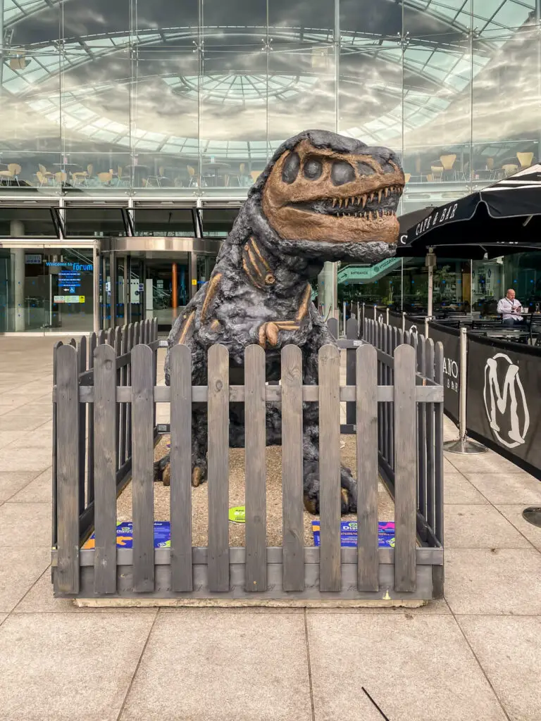 brown dinosaur behind a wooden fence