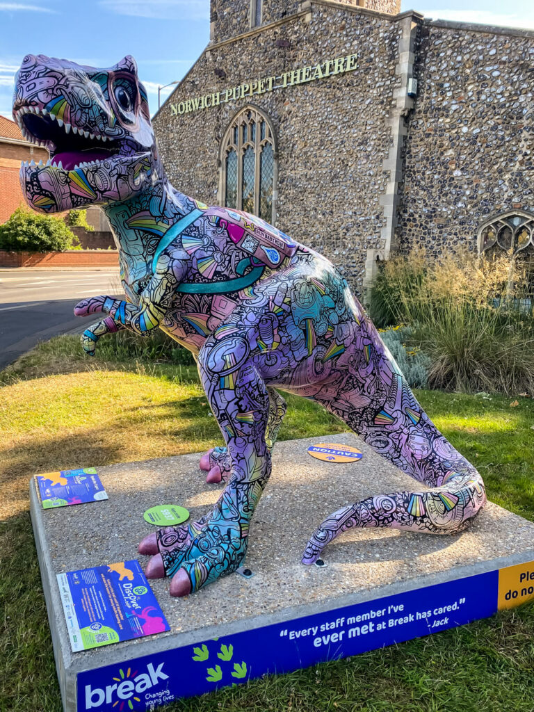 colorful dinosaur in front of church that is now norwich puppet theatre