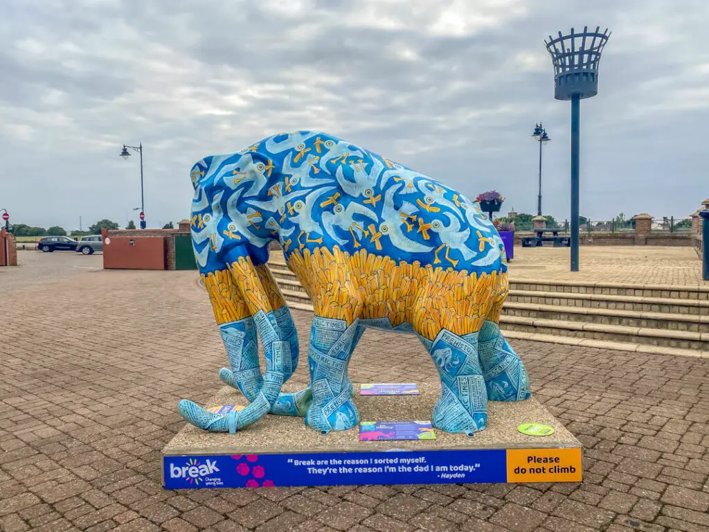 blue mammoth with yellow strip across the middle (when you look closer the blue is seagulls and the yellow is chips) with a beacon (not lit) in the background