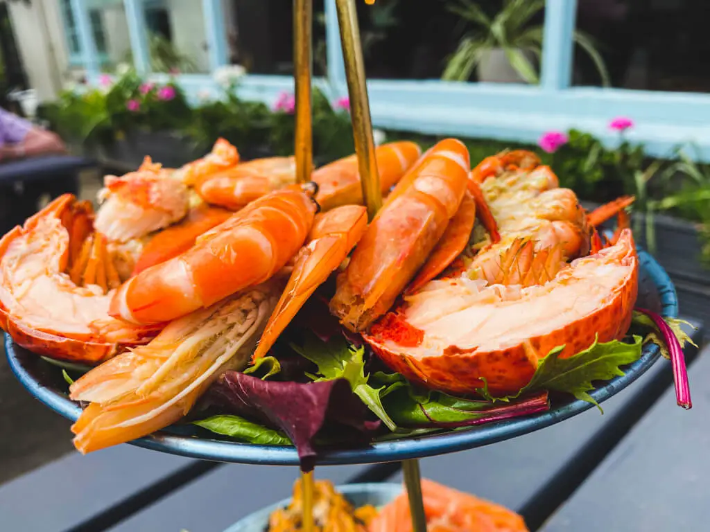 top level of tiered seafood platter has lobster and large prawns