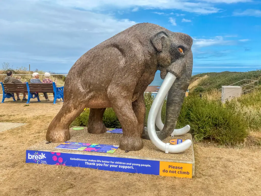 realistic looking mammoth sculpture, brown with white tusks