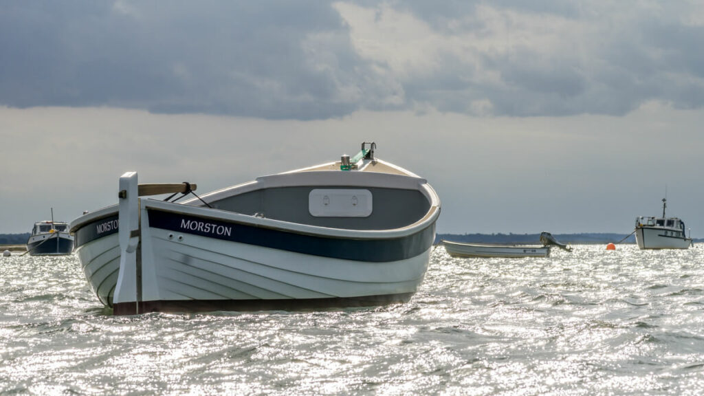 white boat with blue trim and morston written on it in the water