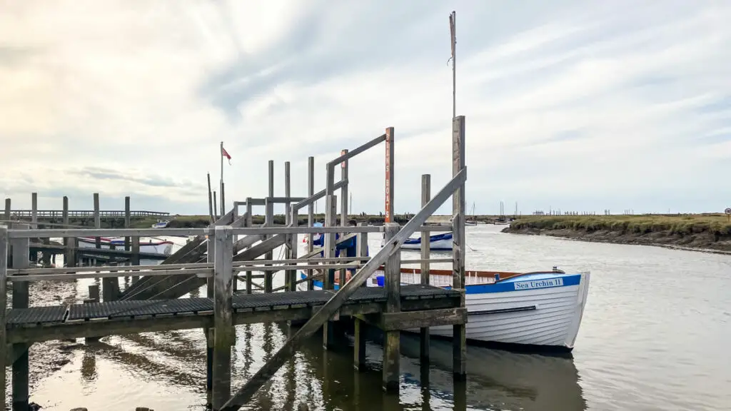 dock with boat that is white with blue trim at morston quay