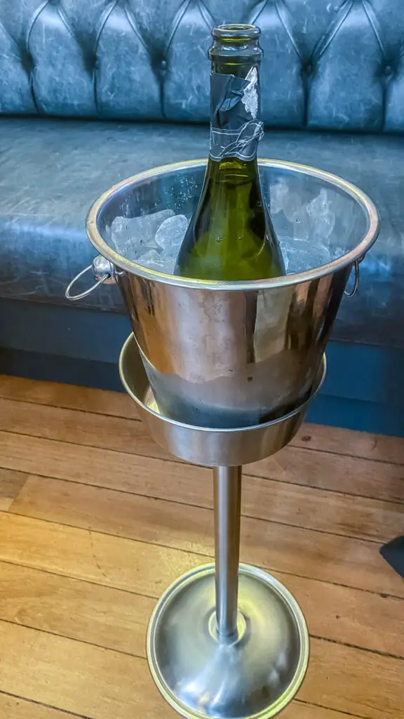 bottle of prosecco chilling in stainless steel bucket of ice on a stand