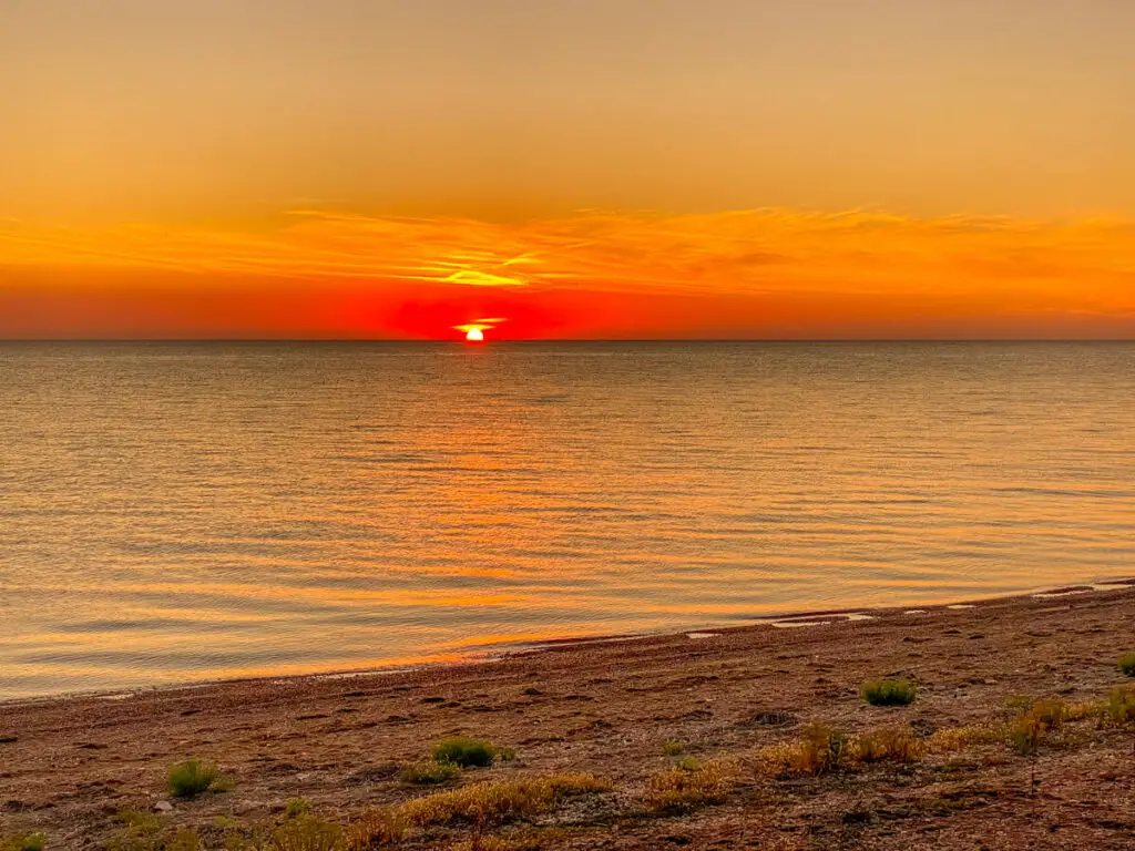 looking over the water of The Wash to see the sun dipping blow the horizon