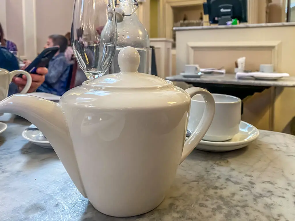 white teapot with cup and saucer in the background