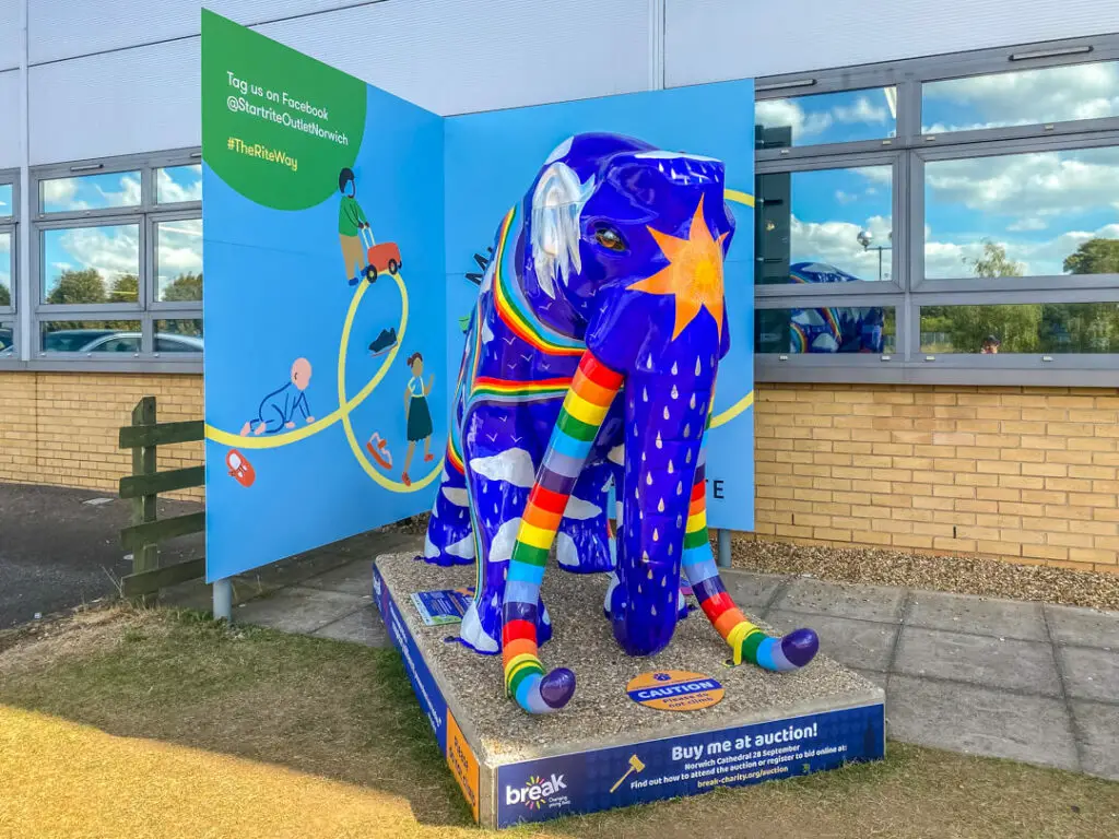 rainbow themed mammoth, with sun on forehead and clouds and raindrops on body