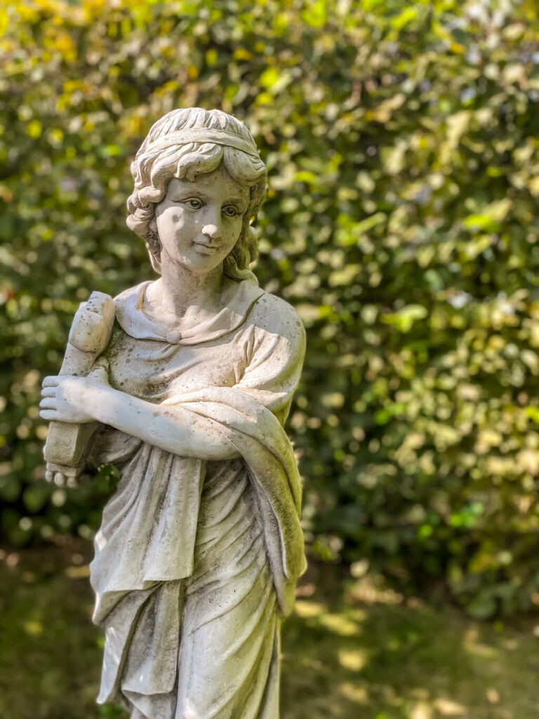 sculpture of a lady with blurred leaves in the background