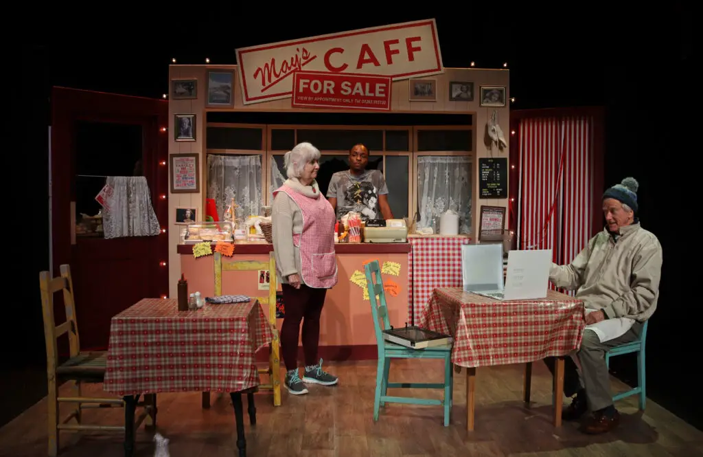 may and ken having a conversation in the caff with Daz working behind the counter