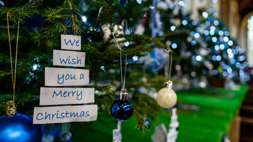 view of the Christmas trees at St peter Mancroft during the Christmas tree festival, one ornament says We wish You a Merry Christmas