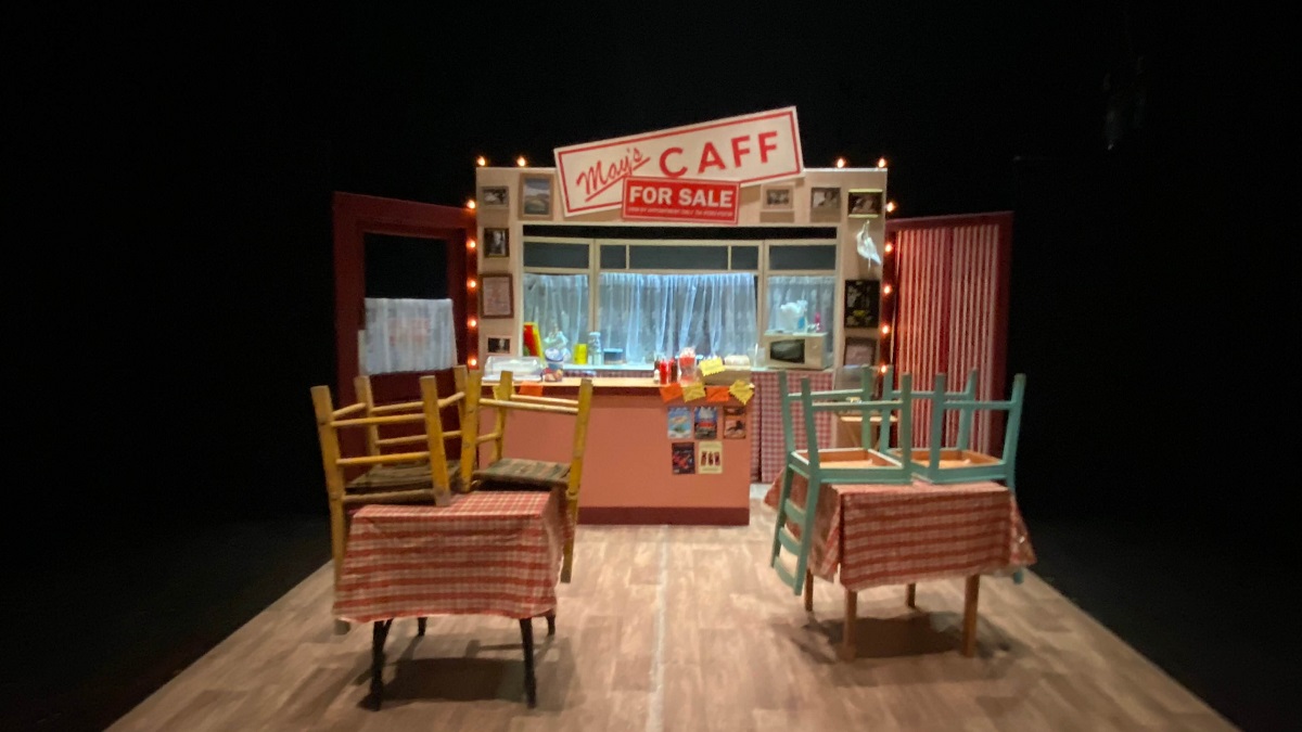 set of tide and time at stage two - the inside of a cafe with counter and two tables with chairs