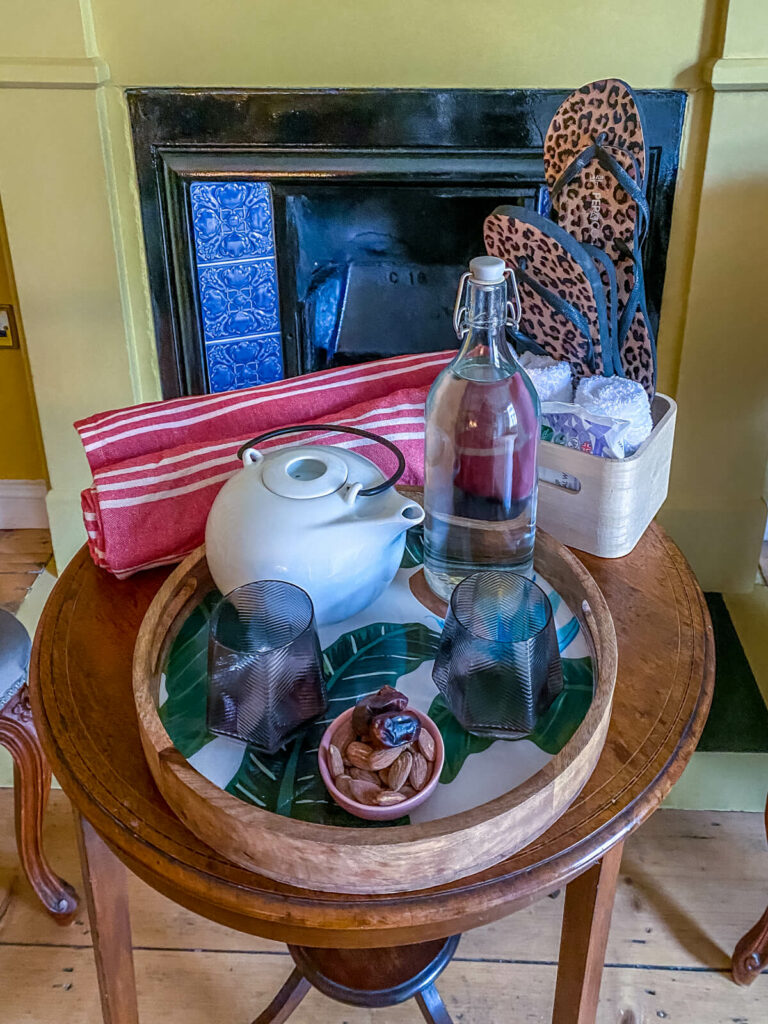 tea, water and snacks on a table with fireplace in the background