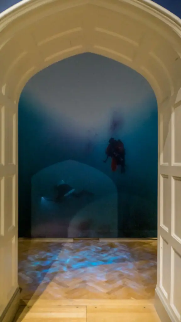 looking through the archway you see a enlarged photo of the barnwell brothers diving with blue wave lights on the floor