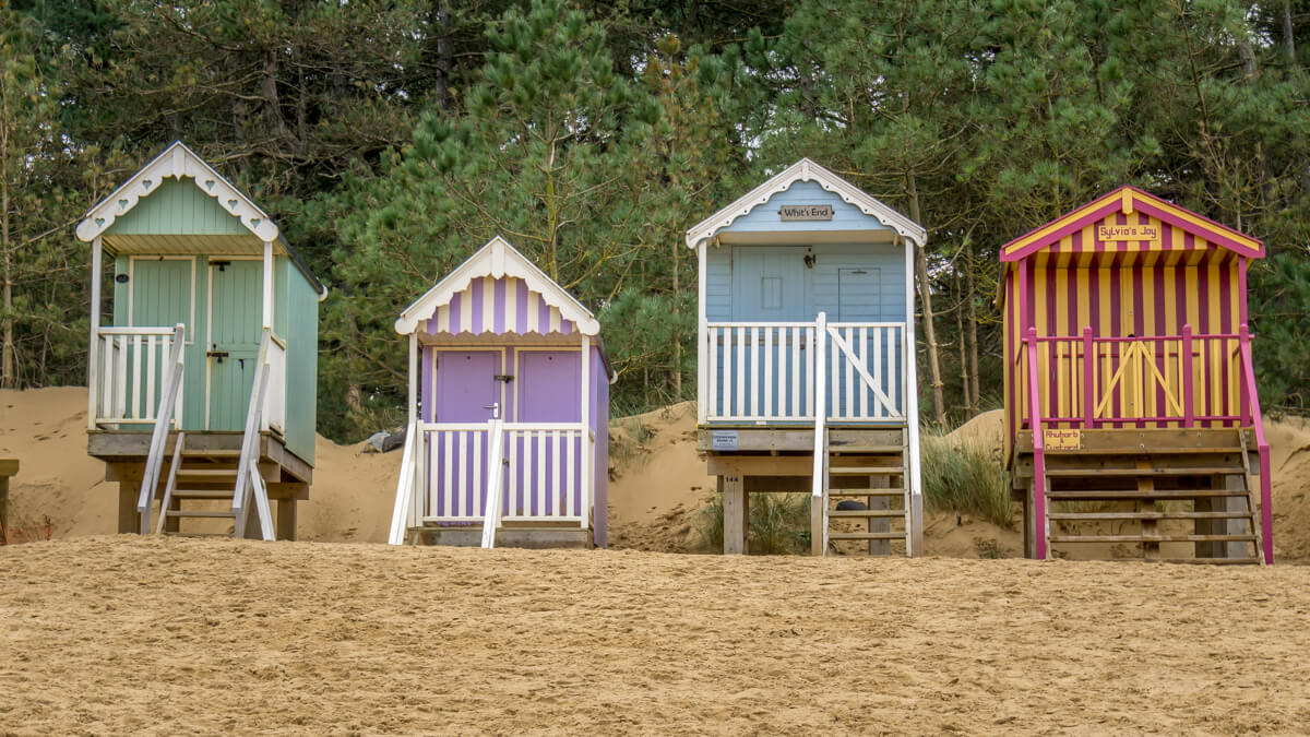 four colourful beach huts on wells beach in norfolk