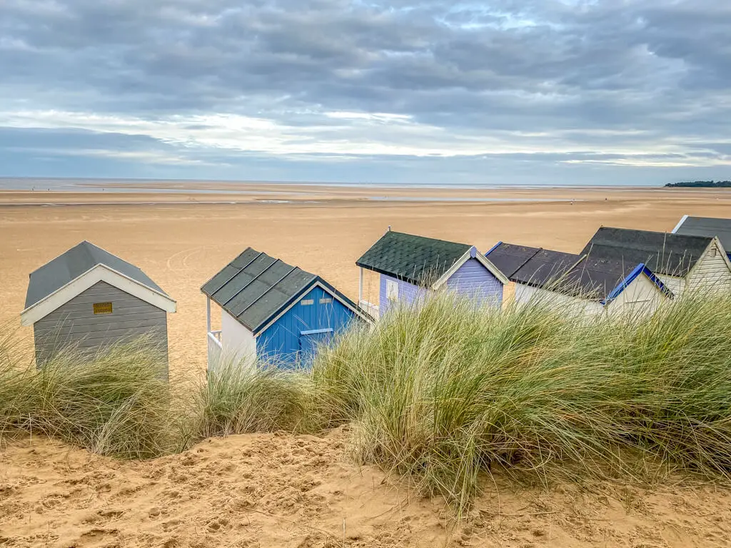 view from behind the colourful beach huts at wells-next-the-sea beach with dunes