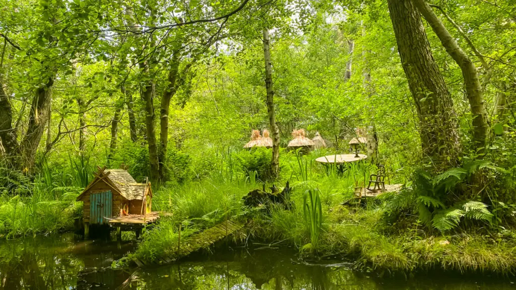 miniature wooden huts of a boogle village next to the river in Bewilderwood
