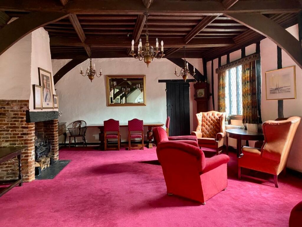 inside the strangers club, a red room with period furniture and wooden beams on the roof