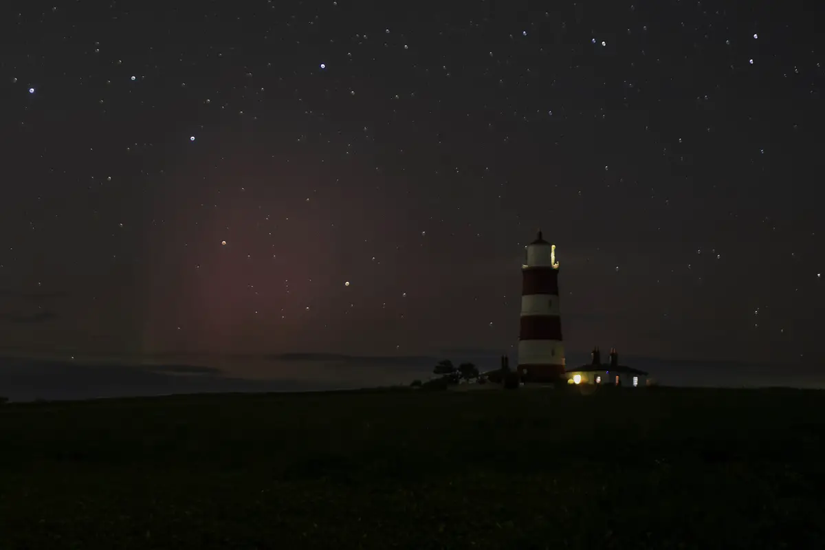 view of the happisburgh lighthouse at night with stars and pink from the Northern lights in Norfolk