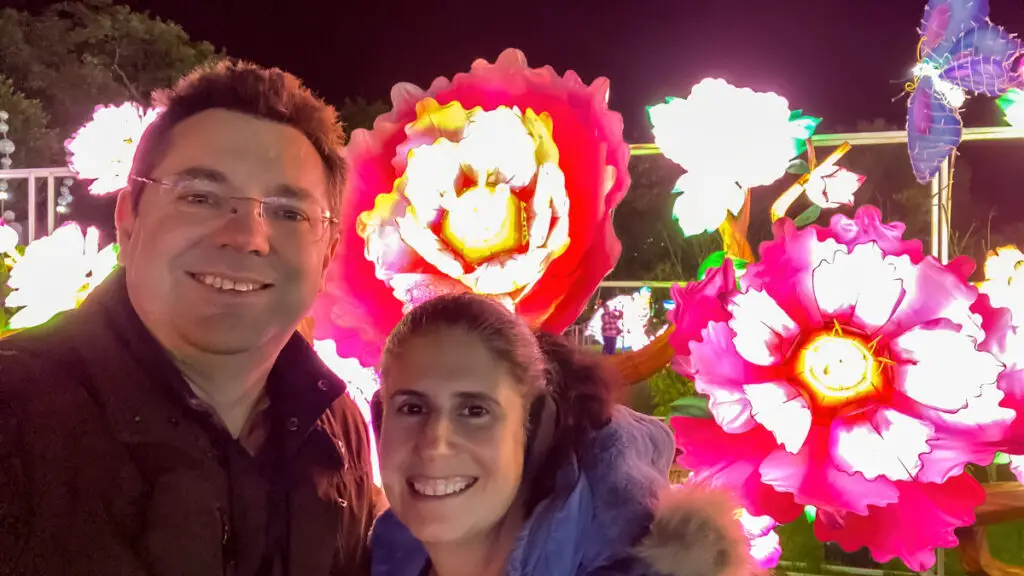 selfie of Russell and Anisa at the Thursford Enchanted Journey of Light in front of illuminated flowers